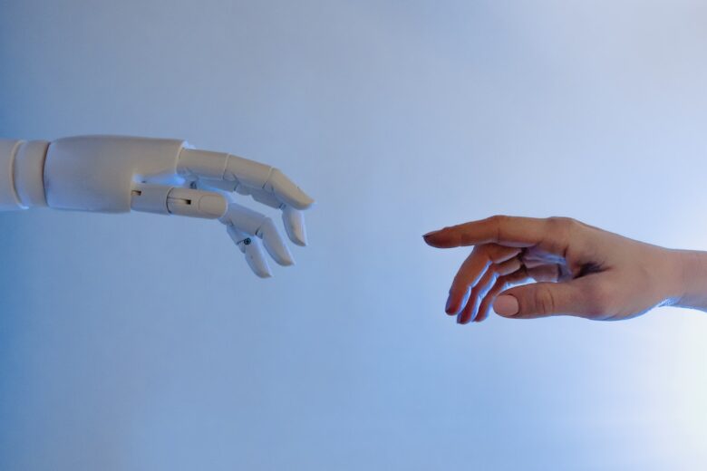 ロボットと人が手を触れようとしている写真